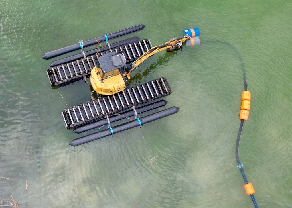 Koparka pływająca z systemem refulacji pracująca na środku zbiornika wodnego – widok z góry.
